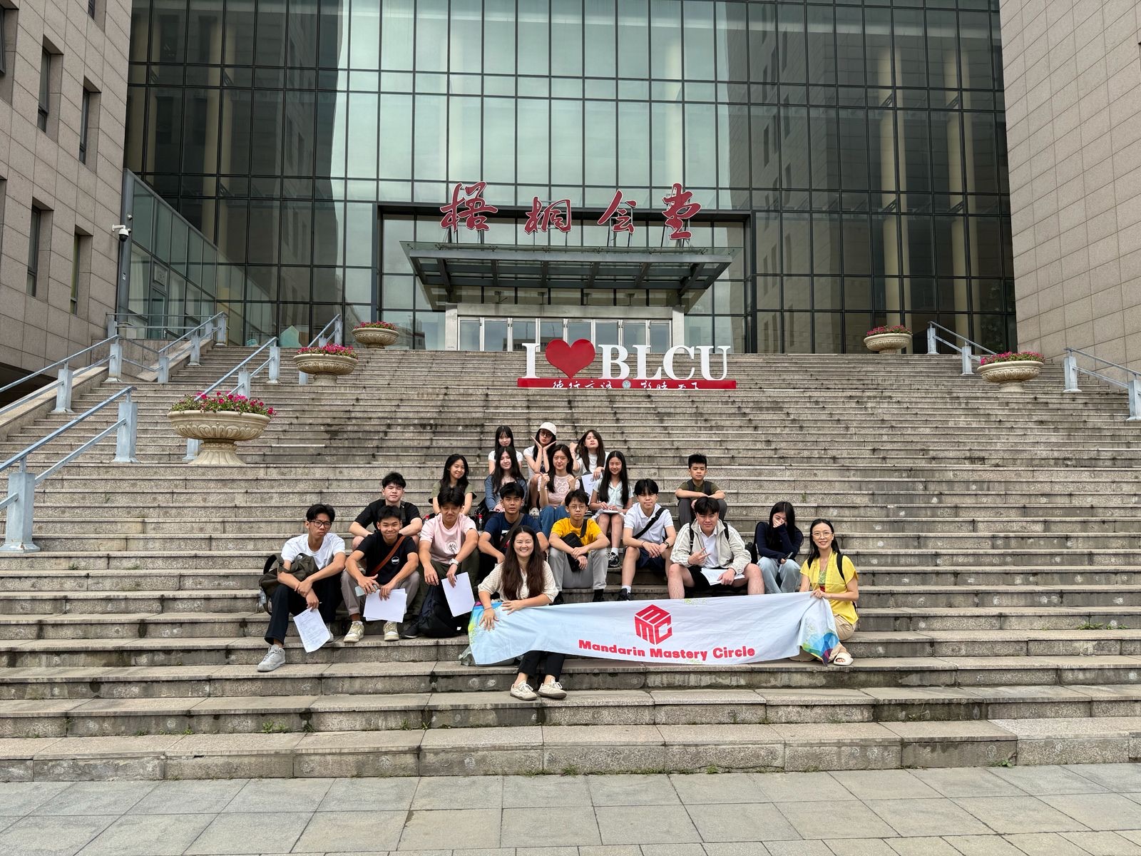 MMC students at BLCU Beijing stairs with banner